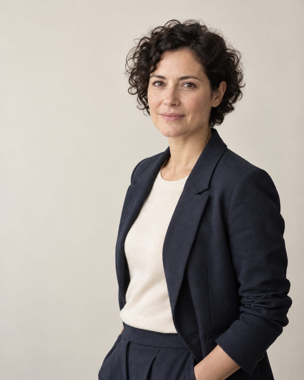 AI-generated layout placeholder portrait of a woman with short dark curls; replace before launch.